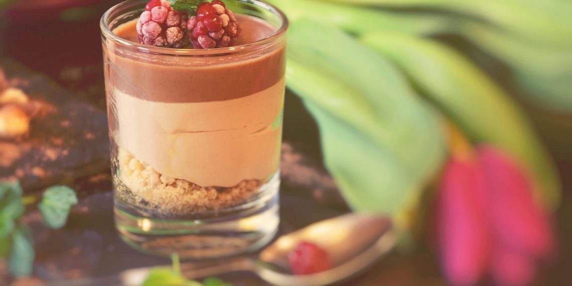 Chocolate mousse with raspberries and mint garnish in a glass cup.