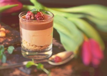 Chocolate mousse with raspberries and mint garnish in a glass cup.