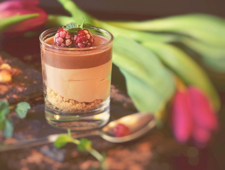 Chocolate mousse with raspberries and mint garnish in a glass cup.