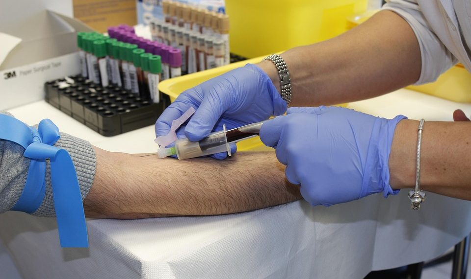Nurse drawing blood with syringe for lab testing.