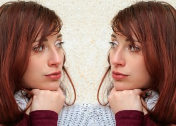 Two women with red hair wearing sweaters face each other.