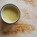 Creamy turmeric latte with cinnamon sprinkle on a light surface.