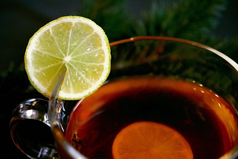 Cup of tea with lemon slice on rim, aromatic hot drink.