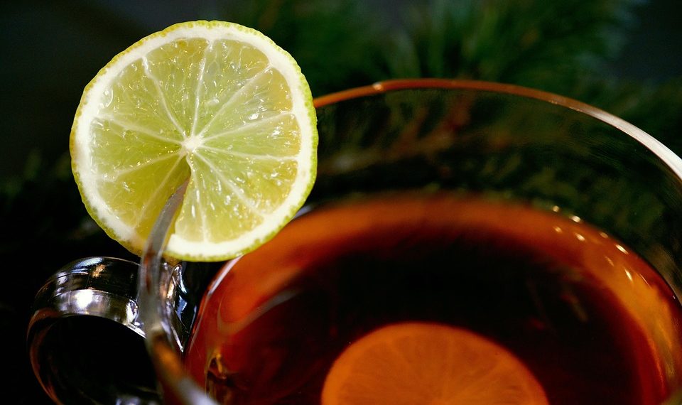 Cup of tea with lemon slice on rim, aromatic hot drink.