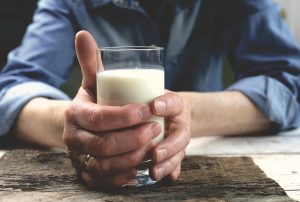 Hands holding a glass of fresh milk.