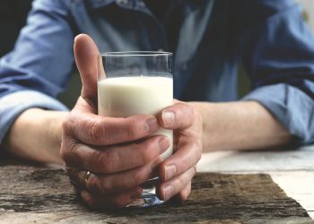 Hands holding a glass of fresh milk.