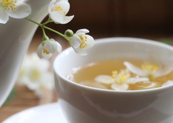 Jasmine tea in a white cup with fresh flowers.