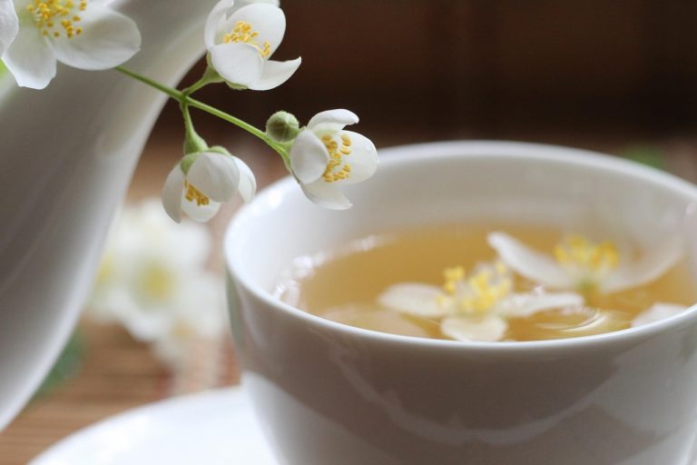 Jasmine tea in a white cup with fresh flowers.