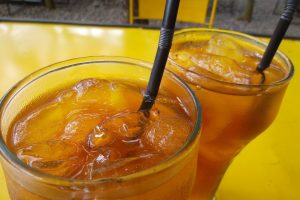 Two glasses of iced tea on a yellow table.