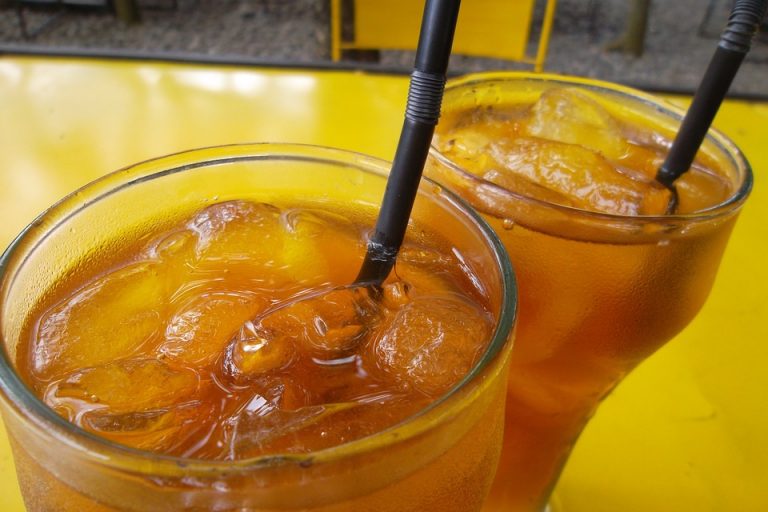 Two glasses of iced tea on a yellow table.