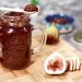 Homemade fig jam in a jar with fresh figs and sliced bread.