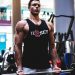Man lifting weights in gym in Jersey tank top.