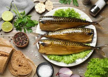 Smoked mackerel on a plate with herbs, bread, and spices.