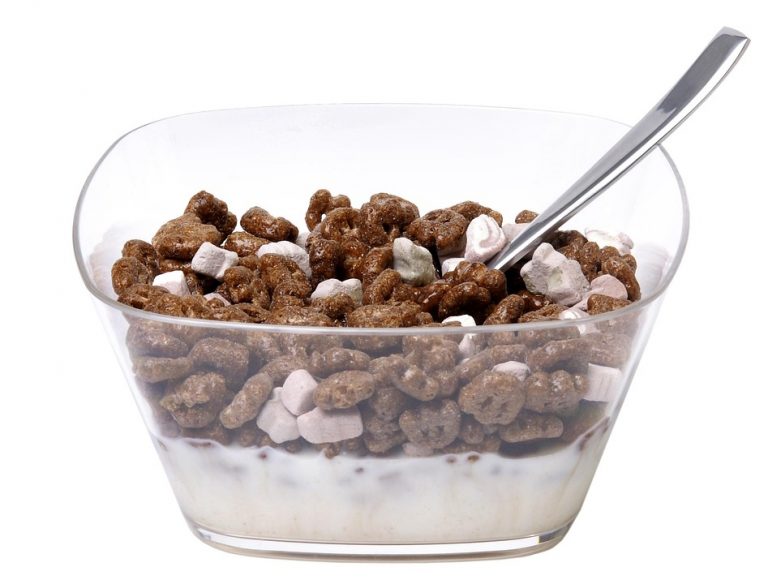 Chocolate cereal and marshmallows in a bowl with milk and spoon.