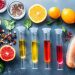 Fresh ingredients and colorful liquids in test tubes on a kitchen surface.