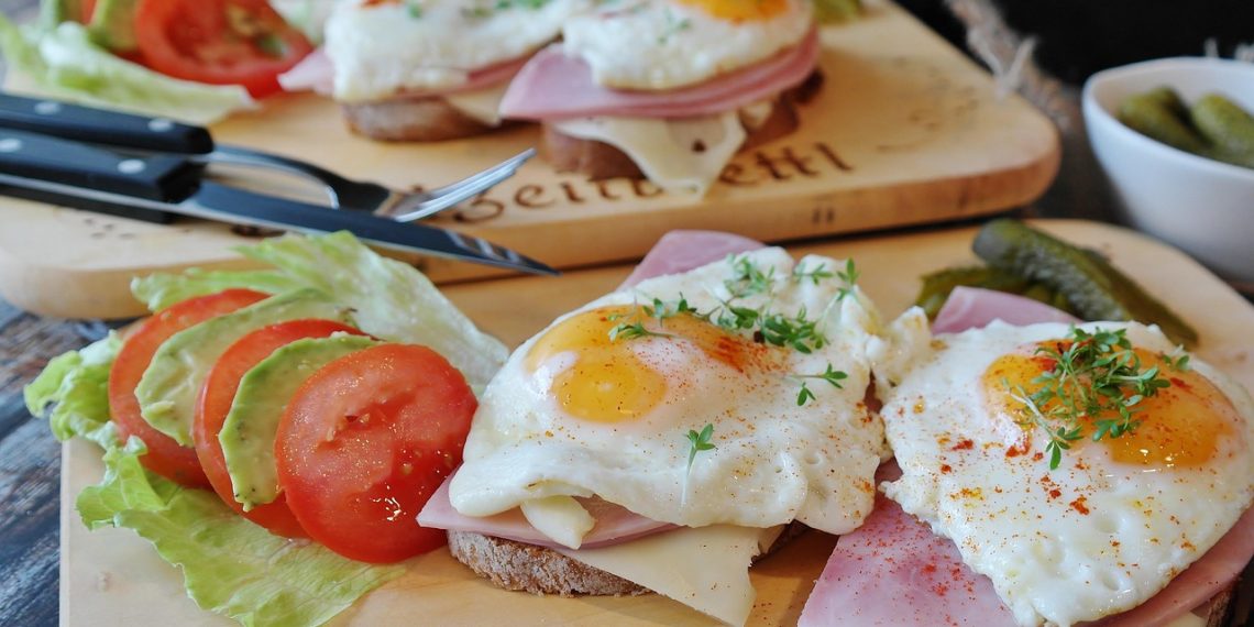 open-faced sandwich with eggs, ham, and vegetables