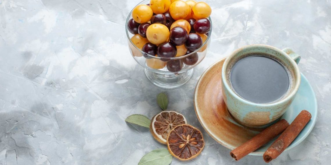 Bowl of yellow and purple berries next to coffee with spices.