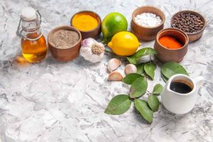 Spices, garlic, and lemons on marble surface with olive oil bottle.