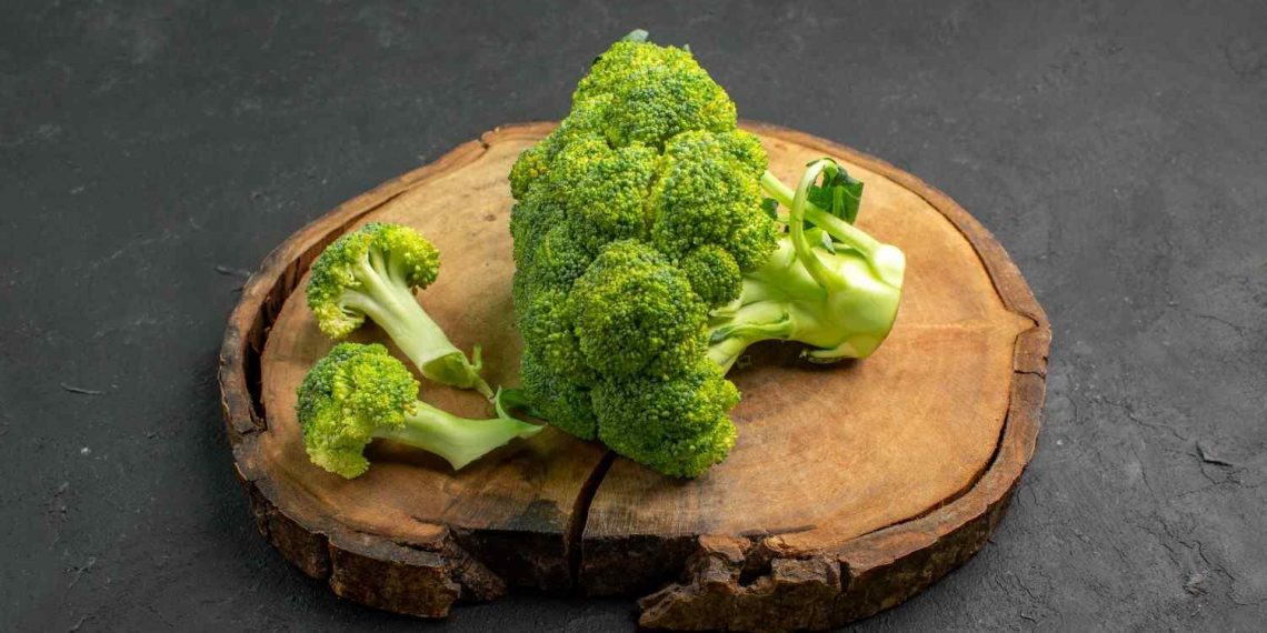 Fresh broccoli florets on a wooden board.