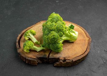 Fresh broccoli florets on a wooden board.