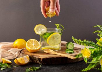 Squeezing lemon into glass with cucumber slices and mint.