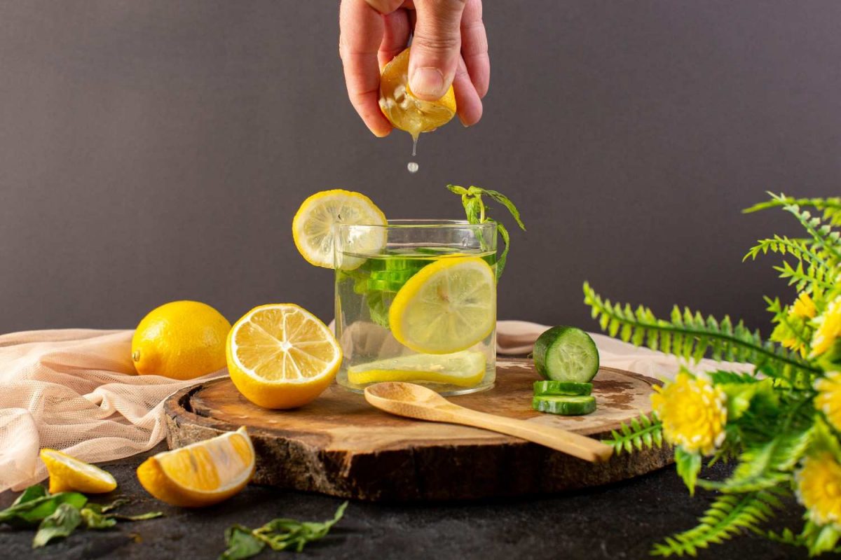 Squeezing lemon into glass with cucumber slices and mint.