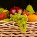 Mixed fruit basket with grapes, apple, pear, and strawberries arranged in a woven container.