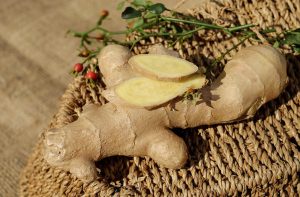 Whole and sliced fresh ginger on woven mat.