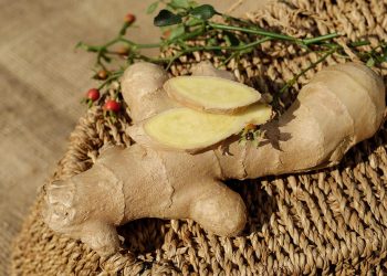 Whole and sliced fresh ginger on woven mat.
