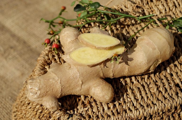 Whole and sliced fresh ginger on woven mat.