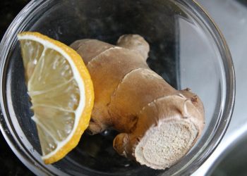 Ginger root and lemon slice in a glass bowl.