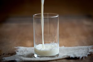Pouring milk into a glass on a wooden table.