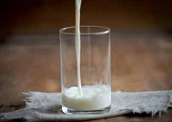 Pouring milk into a glass on a wooden table.
