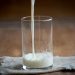 Pouring milk into a glass on a wooden table.