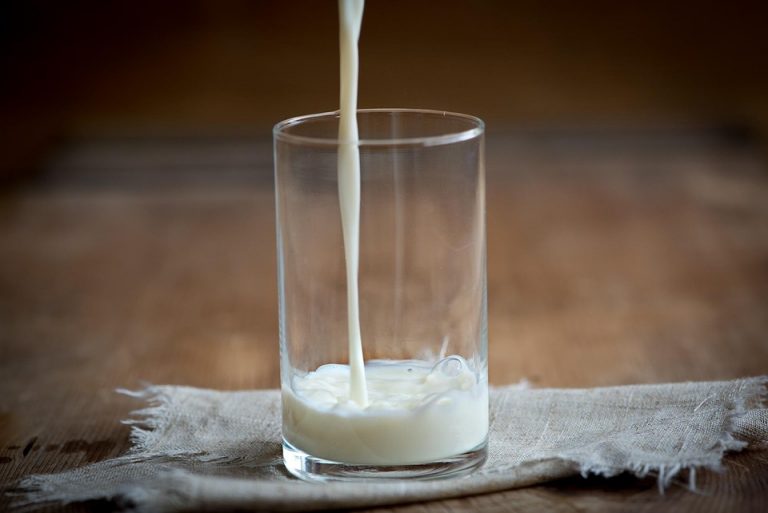 Pouring milk into a glass on a wooden table.