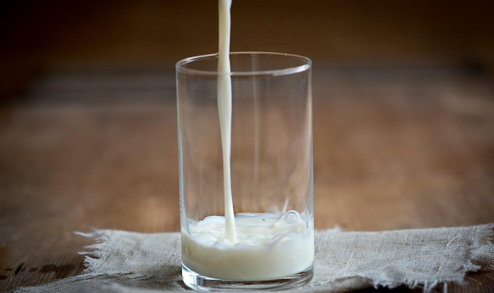 Pouring milk into a glass on a wooden table.