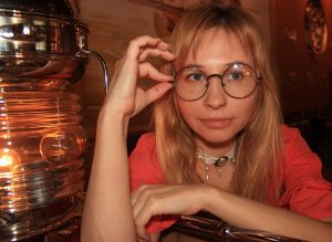 Woman with glasses looking intently, expressing curiosity.