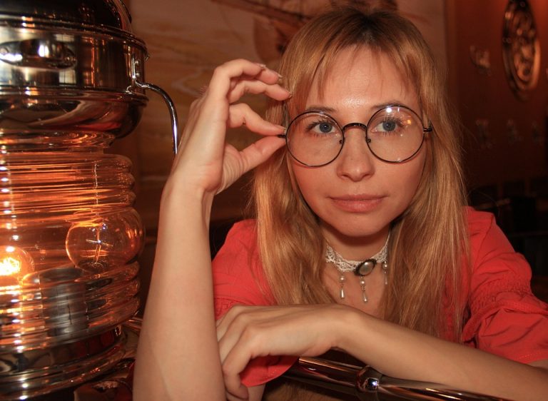 Woman with glasses looking intently, expressing curiosity.