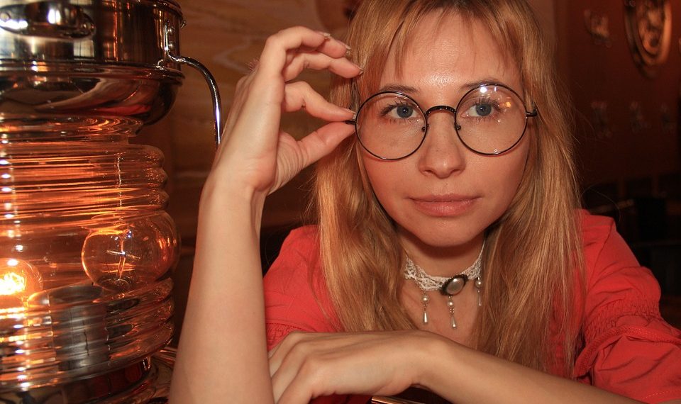 Woman with glasses looking intently, expressing curiosity.