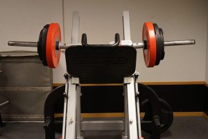 Barbell setup on gym squat machine.
