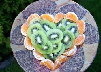 Kiwi and tangerine slices artfully arranged on a decorative platter.