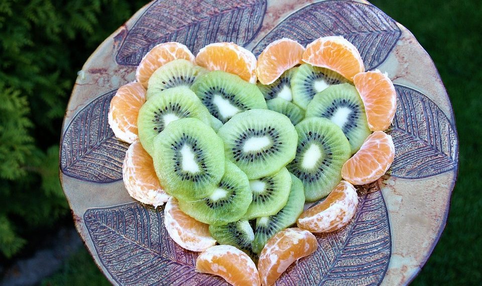 Kiwi and tangerine slices artfully arranged on a decorative platter.