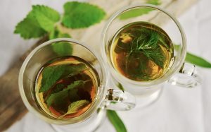 Two cups of herbal tea with fresh mint leaves floating.