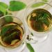 Two cups of herbal tea with fresh mint leaves floating.