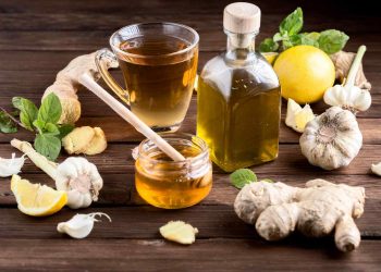 Herbal tea with ginger, garlic, lemon, and honey on wooden table.