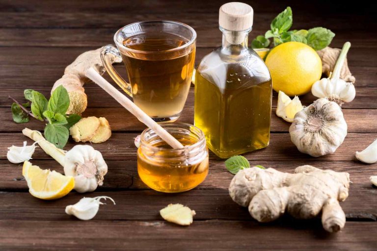 Herbal tea with ginger, garlic, lemon, and honey on wooden table.