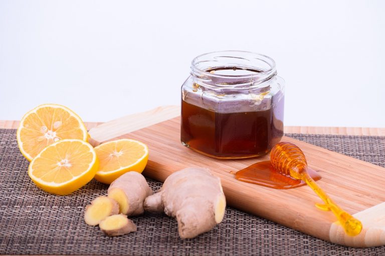 Lemon, ginger, and honey on a wooden platter for a natural remedy.