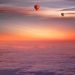 Two hot air balloons floating under a colorful sunset sky.