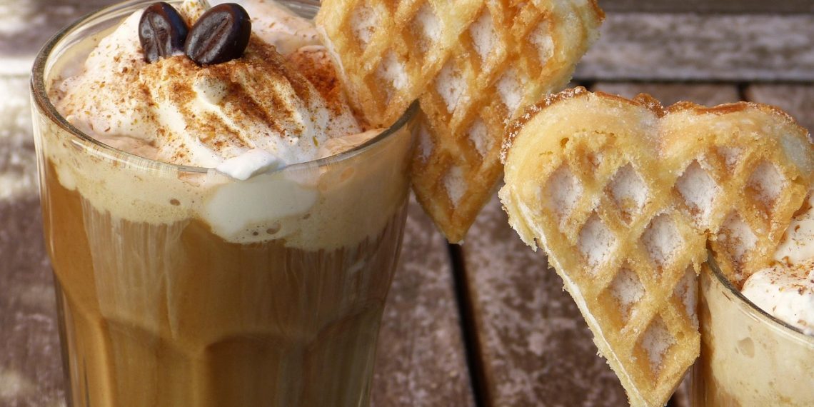 Cinnamon-topped latte with whipped cream and heart-shaped waffles.