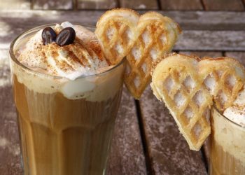 Cinnamon-topped latte with whipped cream and heart-shaped waffles.